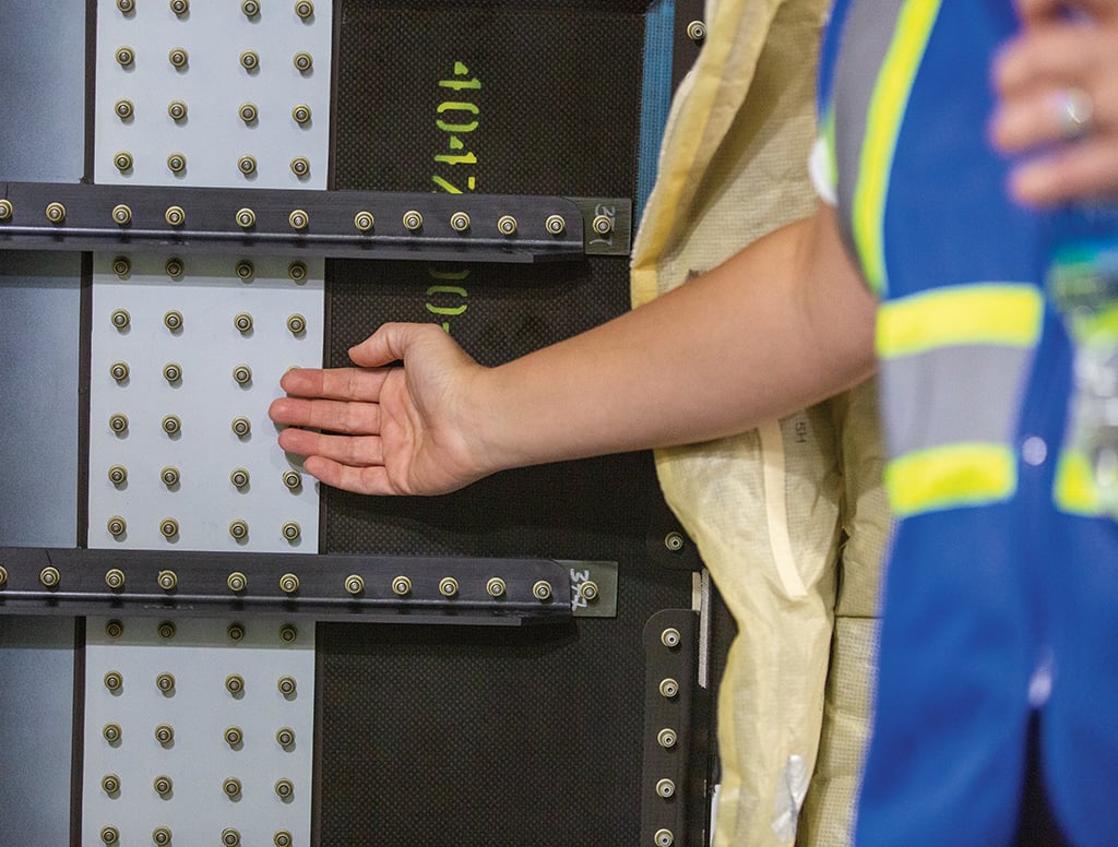 Worker hand indicating gap between splice plates (lighter color) and fuselage section
