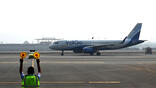 Rear view of air marshal in front of IndiGo jet on runway