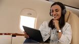 passenger on a business jet holding an iPad and listening to music