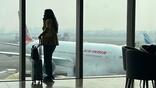 air india jet in background as female passenger looks out window