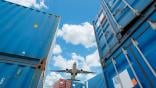 aircraft flying over shipping containers