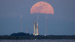 Space Launch System rocket and Orion spacecraft on launcher against rising Moon